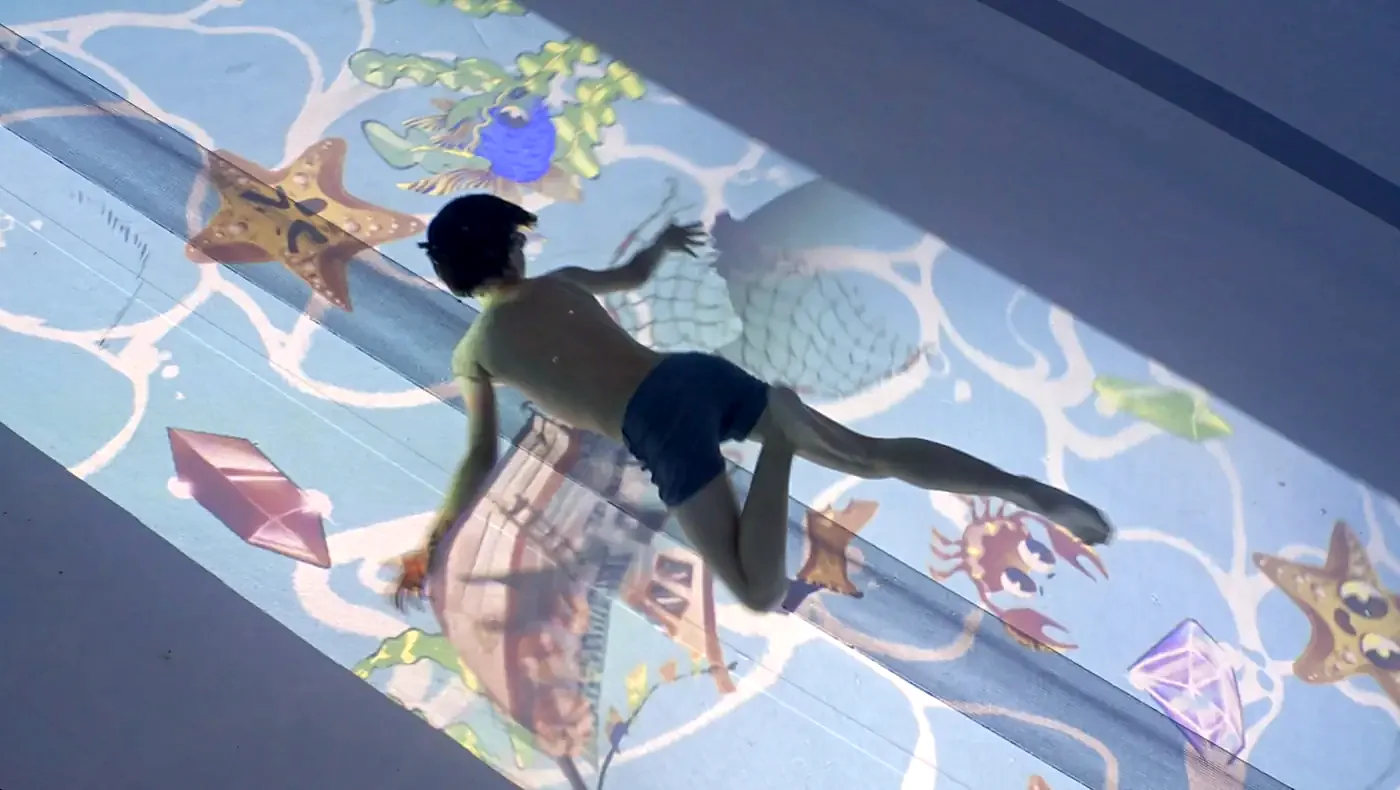 A child swims over a projected seabed with starfish