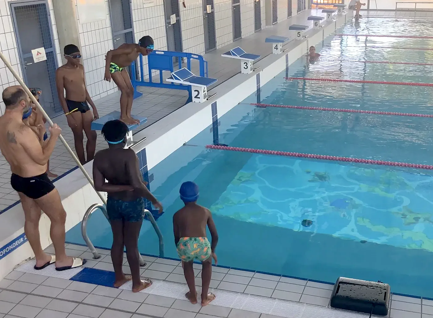 Children at the pool edge ready for a projected swim lesson